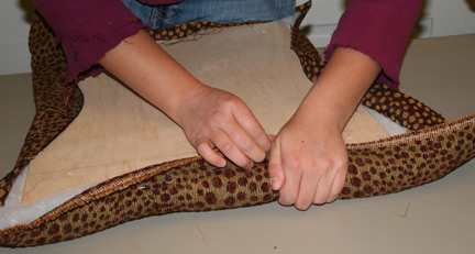 hands stretching fabric over the plywood/foam seat