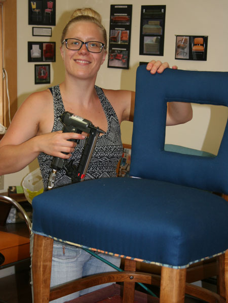 Upholstery apprentice stapling fabric on her window back chair