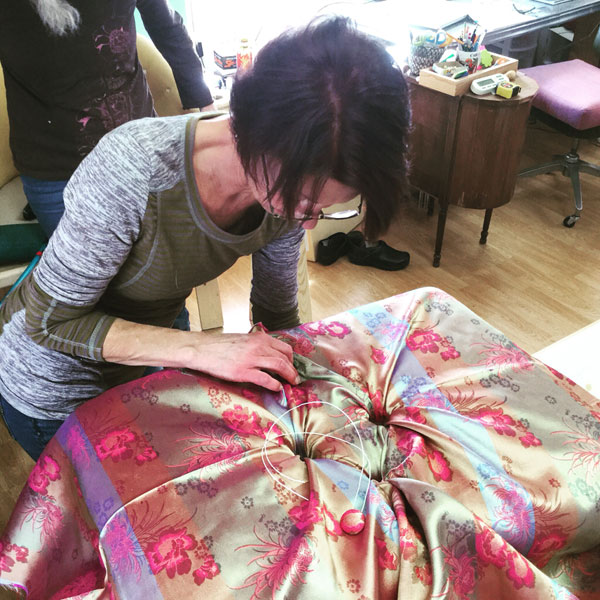 Upholstery student works on her button-tufted ottoman